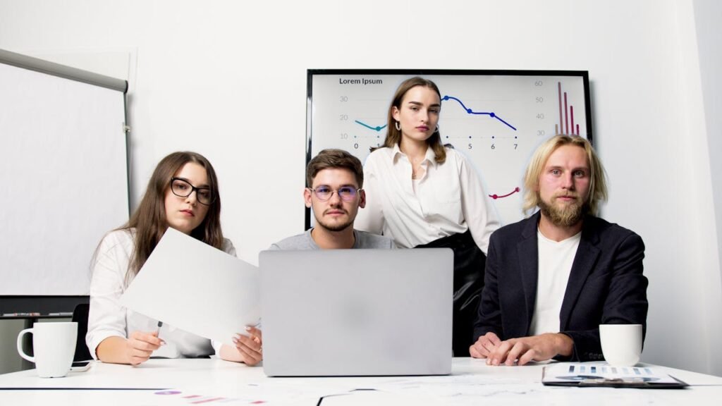 Diverse group of professionals collaborating in an office with charts and laptops.